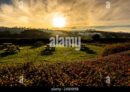 Tramonto su alcuni tavoli da picnic nella gloriosa Derbyshire Peak District National Park, tabelle vuote su un gelido freddo Gennaio sera al tramonto Foto Stock