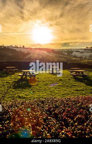 Tramonto su alcuni tavoli da picnic nella gloriosa Derbyshire Peak District National Park, tabelle vuote su un gelido freddo Gennaio sera al tramonto Foto Stock