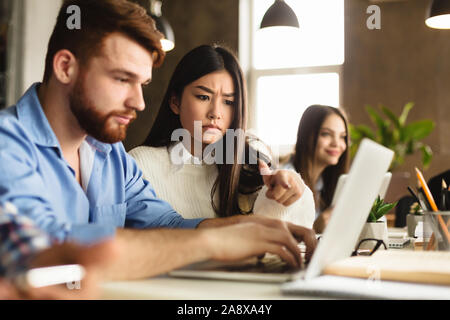 Studiare insieme. Amici dell'università con il computer portatile nella libreria Foto Stock