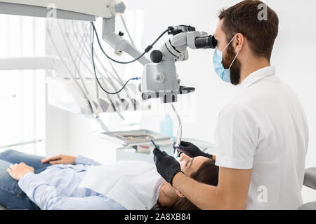 Vista laterale del dentista professionale utilizzando moderne tecnologie di trattamento Foto Stock