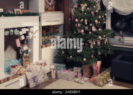 È Notte Santa, l'albero di Natale decorato è nel soggiorno e qui di seguito sono avvolti i regali di Natale. Immagine autentica di una festa privata. Foto Stock