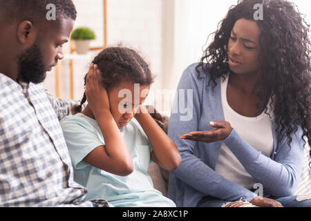 Bambina chiudendo i suoi orecchi per non ascoltare i genitori scolding Foto Stock