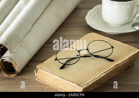 Un libro con un vecchio stile occhiali, una lente di ingrandimento e arrotolato antiche pergamene Foto Stock