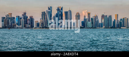 Doha, skyline del Qatar dalla Corniche vista diurna con il golfo arabo in primo piano e le nuvole nel cielo sullo sfondo Foto Stock