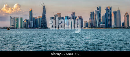 Doha, skyline del Qatar dalla Corniche vista diurna con il golfo arabo in primo piano e le nuvole nel cielo sullo sfondo Foto Stock