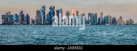 Doha, skyline del Qatar dalla Corniche vista diurna con il golfo arabo in primo piano e le nuvole nel cielo sullo sfondo Foto Stock