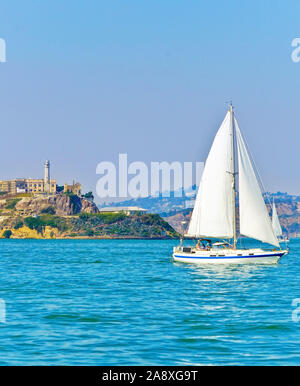 Vista dell'isola di Alcatraz con una barca a vela che passa sulla baia di San Francisco a San Francisco. Foto Stock
