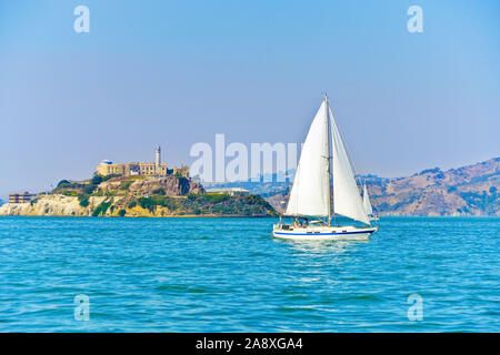 Vista dell'isola di Alcatraz con una barca a vela che passa sulla baia di San Francisco a San Francisco. Foto Stock