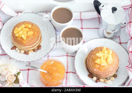 La prima colazione per due persone. American pancake con marmellata di arancia e i dadi sulle piastre di vintage e bianco 2 tazze di caffè. Vista superiore Foto Stock