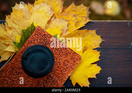 Ciao autunno. Primo piano sul notebook, foglie di giallo e la tazza di caffè sul banco di prova all'aperto nel parco d'autunno. Foto Stock