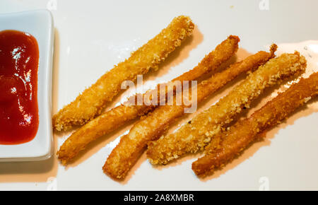 Lunga pepite di pollo strisce con ketchup su uno sfondo bianco. Vista superiore Foto Stock