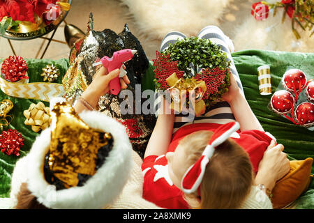 Vista superiore della moderna madre e figlia seduti sul divano nel soggiorno moderno a Natale rendendo decorazione artigianale insieme. Foto Stock