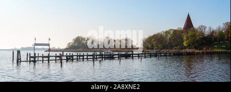 Lungo pontile in legno nel porto di yacht presso la chiesa in una baia dell'isola di Poel vicino a Wismar nel Mar Baltico, Germania, blu cielo con copia spazio, panora Foto Stock