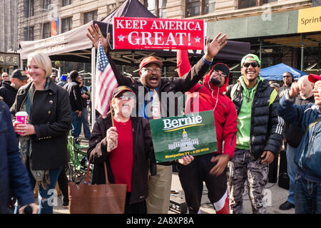 New York, NY, STATI UNITI D'AMERICA. Xi Nov, 2019. New York City veterani della parata del giorno, oggi segna il centesimo anniversario dell'armistizio terminando i combattimenti della prima guerra mondiale, ha visto la partecipazione di un numero di persone che protestano Presidente Trump, che ha parlato durante la cerimonia di apertura e un numero minore di pro-Trump sostenitori. Una donna tenendo un cartello che recita "Bernie Montpelier VT - 5-25-2019' si trova di fronte a tre uomini afro-americano, uno dei quali tiene alto un cartello che recita "Mantenere l'America grande.' Credit: Ed Lefkowicz/Alamy Live News Foto Stock