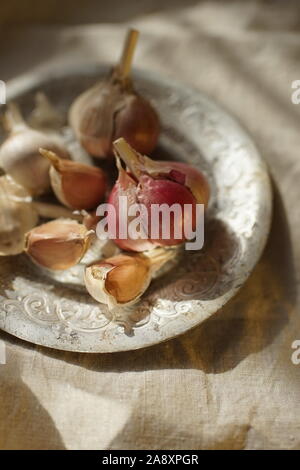 Bulbi di aglio e chiodi di garofano in lastra d'argento sul tavolo. Foto Stock
