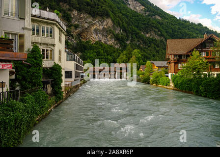 Interlaken, Svizzera - Agust 24, 2010: il fiume Aare e vintage stile Svizzero edifici lungo la riva nella zona della città vecchia con sfondo di montagna di IO Foto Stock