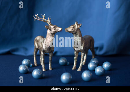 Golden natale renne figurine con decorazioni su sfondo blu. Maschio e femmina Foto Stock