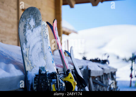 Immagine di multi-colore di sci e snowboard nella neve in inverno resort nel pomeriggio. Sfondo sfocato. Foto Stock