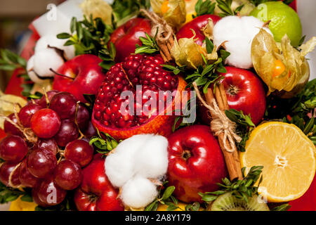 Composizione di freschi frutti luminosi. Bouquet di frutta da melograno, uva, mele, kiwi, arancio, limone, marrone e cotone Foto Stock