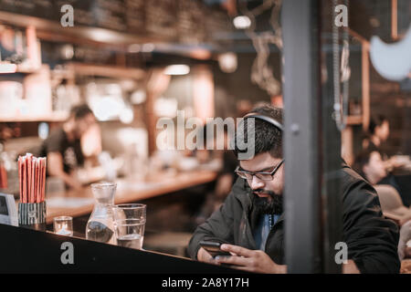 Portland, Oregon - Nov 10, 2019 : un uomo seduto e guardando a smart phone al cafe nel centro di Portland Foto Stock