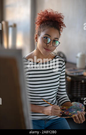 Giovane artista con gli occhiali per il mescolamento di vernici Foto Stock