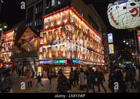 OSAKA, GIAPPONE - 13gennaio 2019: colorata architettura nel quartiere Shinsekai di Osaka di notte. Un sacco di persone può essere visto. Foto Stock