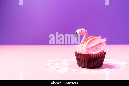 Fenicottero rosa cupcake sul rosa pastello e sfondo viola. Buon compleanno card. Copia dello spazio. Close-up. Foto Stock