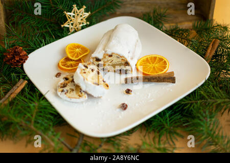 Mela cotta stollen sulla piastra bianca tra le decorazioni di Natale Foto Stock