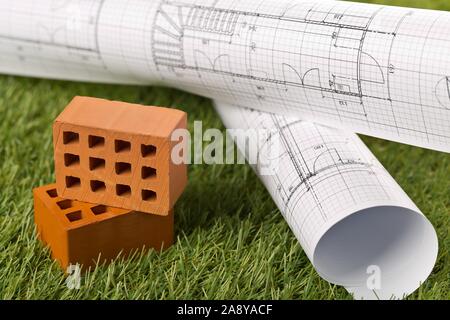 Gli schemi architetturali con mattoni in miniatura sul verde prato di sfondo - della costruzione o acquisto di concetto, il fuoco selettivo Foto Stock