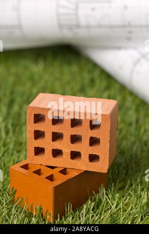 Gli schemi architetturali con mattoni in miniatura sul verde prato di sfondo - della costruzione o acquisto di concetto, il fuoco selettivo Foto Stock