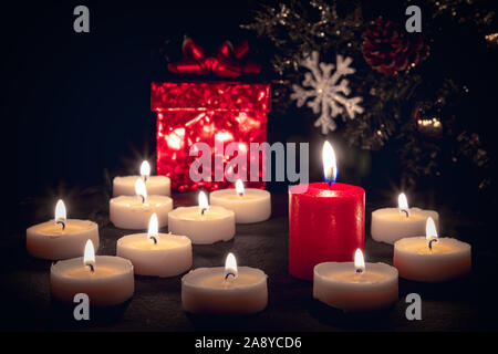 Natale candele accese di notte davanti a una confezione regalo rossa Foto Stock