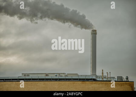 Fumo nero su un cielo grigio, venendo da una grande ciminiera sulla sommità di una fabbrica. Danimarca, 10 novembre 2019 Foto Stock