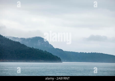 Nuvole basse su San Juan Island come si vede da bordo di un stato di Washington traghetto sul modo da Anacortes di Orcas Island, Washington, Stati Uniti d'America. Foto Stock