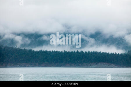 Nuvole basse su San Juan Island come si vede da bordo di un stato di Washington traghetto sul modo da Anacortes di Orcas Island, Washington, Stati Uniti d'America. Foto Stock