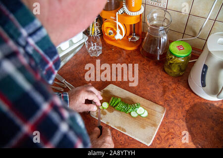 Un vecchio uomo tritare verdure su un tagliere Foto Stock