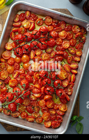 Pomodori ciliegia arrosto con aglio e spezie su un vassoio da forno Foto Stock
