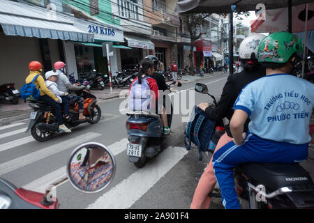 Le madri di prelevare i loro bambini a scuola e li guida home in moto in Nha Trang, Vietnam Foto Stock