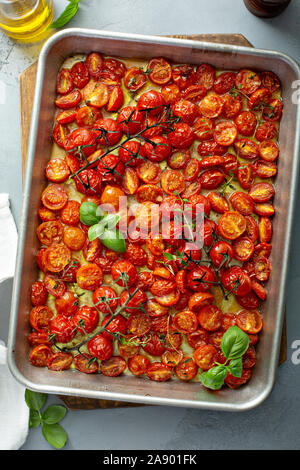 Pomodori ciliegia arrosto con aglio e spezie su un vassoio da forno Foto Stock