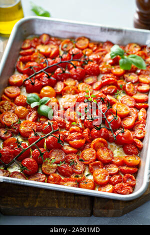 Pomodori ciliegia arrosto con aglio e spezie su un vassoio da forno Foto Stock