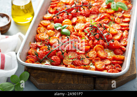 Pomodori ciliegia arrosto con aglio e spezie su un vassoio da forno Foto Stock