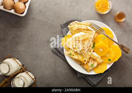 Sottile crepes suzette con fettine di arancia e marmellata per la prima colazione Foto Stock