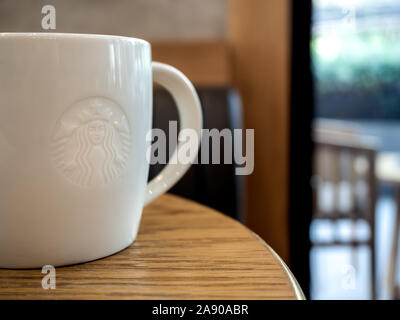 28 Settembre 2019 : Bangkok, Tailandia : Close-up white Starbucks Coffee mug con bassa logo in rilievo sul tavolo di legno in Starbucks Cafe con copia spazio, S Foto Stock