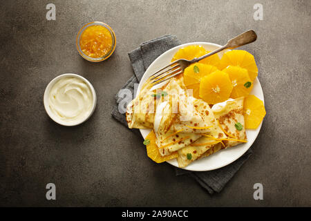 Sottile crepes suzette con fettine di arancia e marmellata per la prima colazione Foto Stock