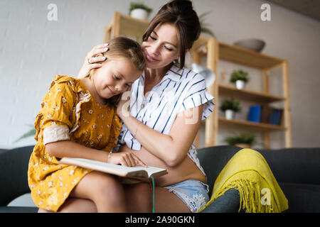 Ritratto di donna incinta e la figlia a leggere un libro nel salotto Foto Stock