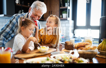 Nonno sorridente che aiuta i ragazzi a cuocere in cucina Foto Stock