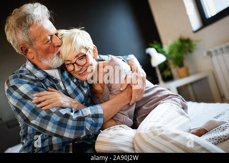 Sorridenti coppia senior abbracciando insieme a casa Foto Stock