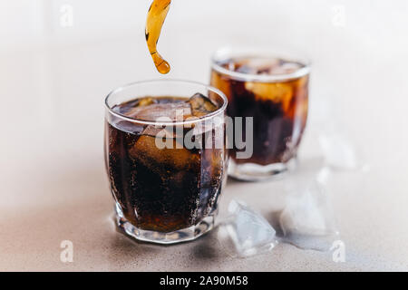 Primo piano di due bicchieri di coca cola con ghiaccio - drink dannosi Foto Stock