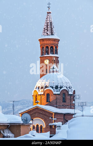 La cupola e la torre campanaria della chiesa cattolica coperto di neve nella città di Alba, Piemonte, Italia settentrionale. Foto Stock