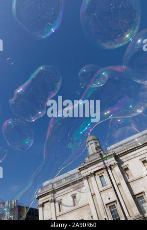 Le bolle create da un suonatore ambulante / street performer , di fronte alla National Gallery, Trafalgar Square, London, Regno Unito Foto Stock