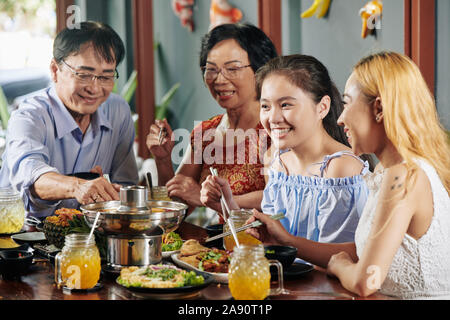 Felice ragazza preteen mangiare una gustosa cena con la sua famiglia nel ristorante quando celebrare qualche evento insieme Foto Stock